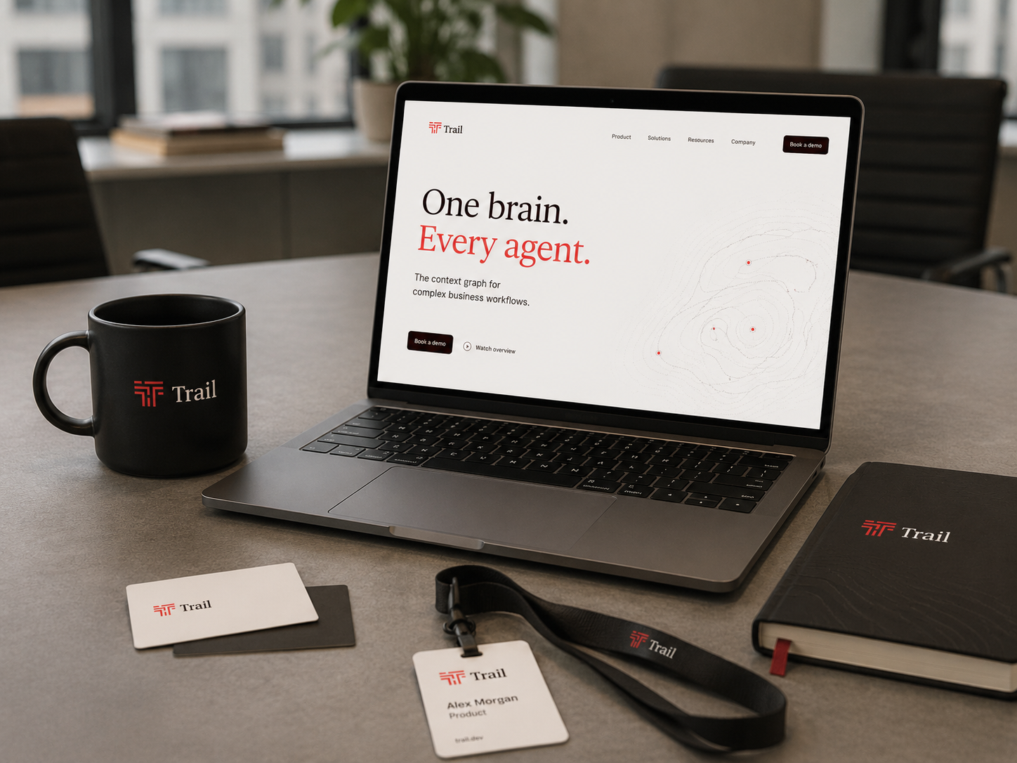 A laptop, mug, cards and lanyard carrying the Trail brand